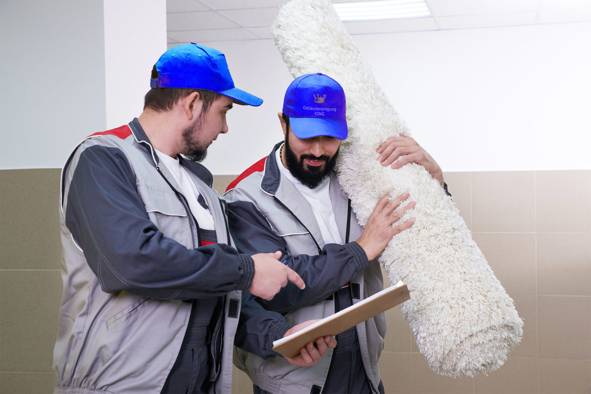 Zwei Männer mit blauen Kappen und einem weissen Teppich